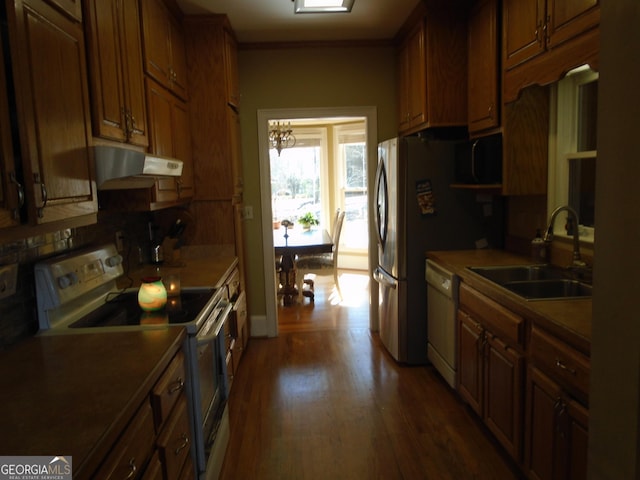 kitchen with backsplash, under cabinet range hood, wood finished floors, white appliances, and a sink