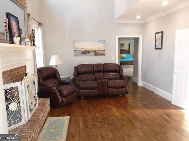 living area with wood finished floors, baseboards, recessed lighting, crown molding, and a brick fireplace