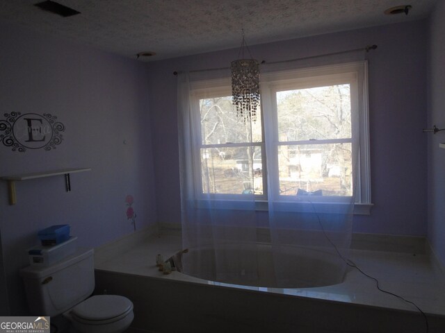 full bath featuring a textured ceiling, a bathtub, and toilet