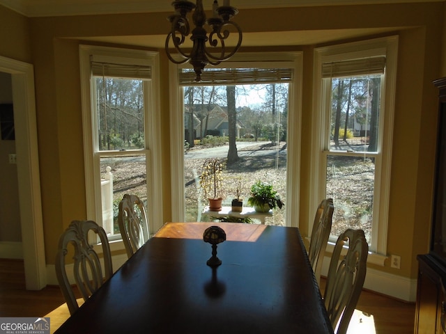 dining area with wood finished floors, a healthy amount of sunlight, baseboards, and a chandelier