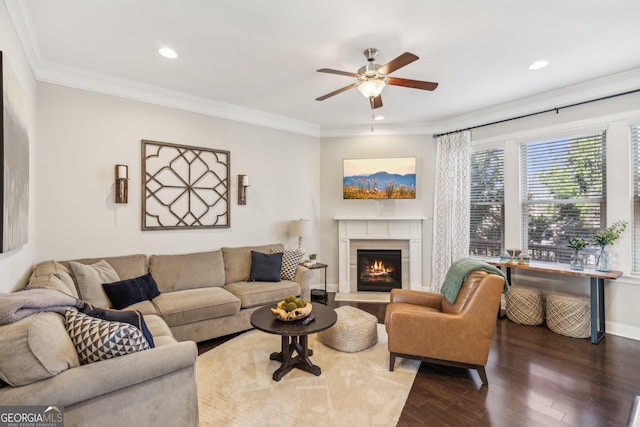 living room with baseboards, dark wood finished floors, a lit fireplace, ornamental molding, and recessed lighting