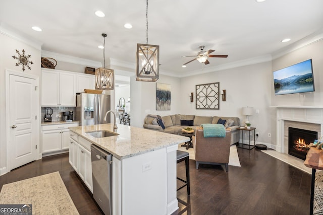 kitchen with a sink, light stone counters, open floor plan, and stainless steel appliances