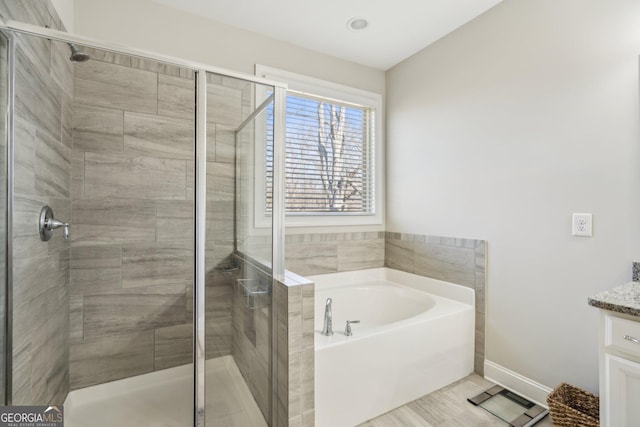 bathroom with a shower stall, vanity, and a garden tub