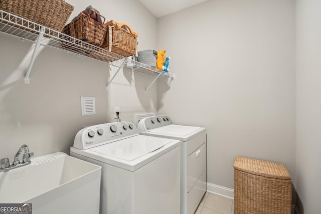 laundry room with a sink, washer and dryer, light tile patterned floors, baseboards, and laundry area