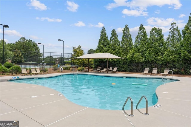 community pool with a patio area and fence