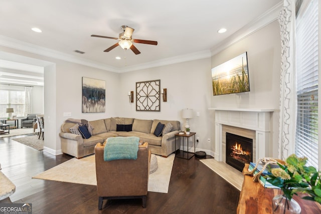 living room featuring visible vents, baseboards, ornamental molding, a fireplace, and dark wood-style floors