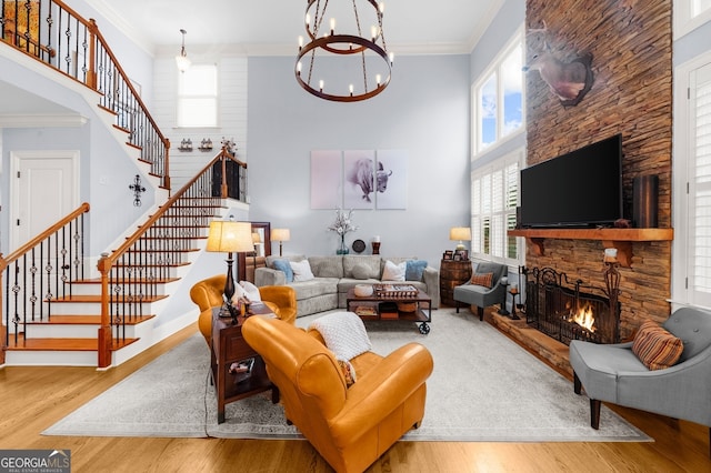 living room with a stone fireplace, crown molding, and wood finished floors