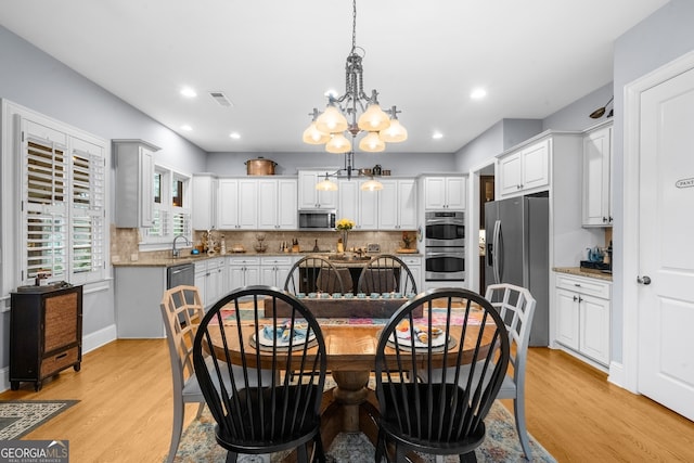 dining space with recessed lighting, visible vents, light wood finished floors, and a chandelier