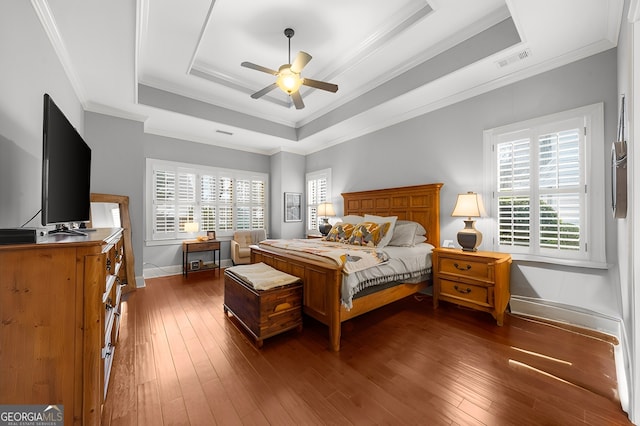 bedroom with a tray ceiling, hardwood / wood-style flooring, visible vents, and ornamental molding