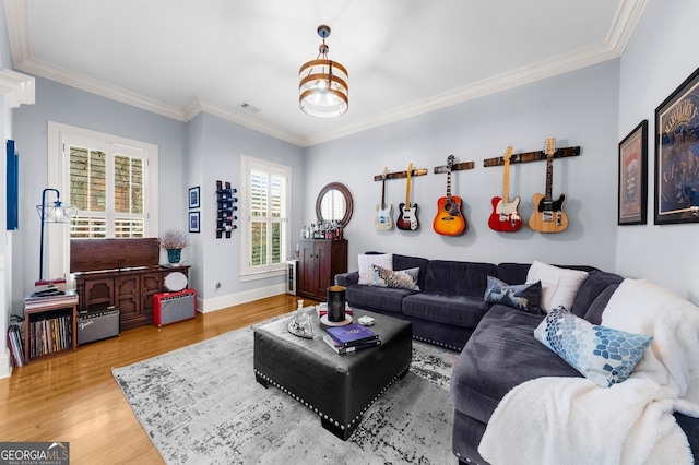 living area featuring baseboards, wood finished floors, visible vents, and ornamental molding