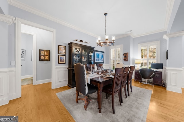 dining space with visible vents, crown molding, light wood-style flooring, an inviting chandelier, and a decorative wall