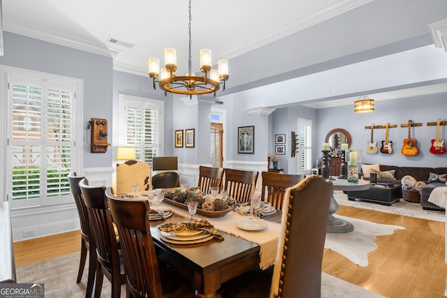 dining area with a wealth of natural light, visible vents, wood finished floors, and ornamental molding