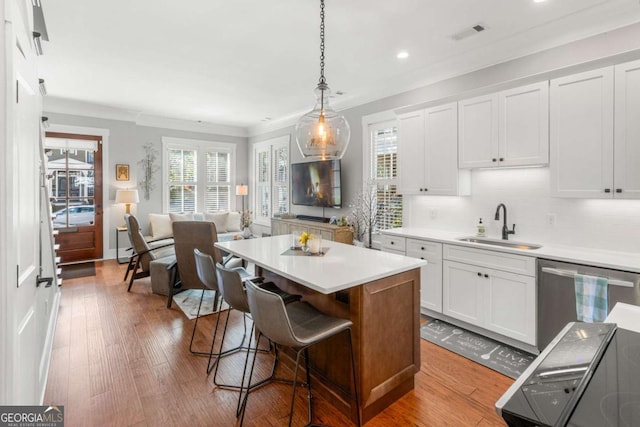 kitchen with visible vents, a breakfast bar, a sink, stainless steel dishwasher, and white cabinetry