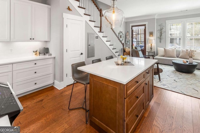 kitchen with a breakfast bar area, dark wood-style floors, a kitchen island, light countertops, and white cabinets