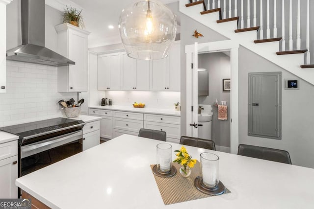 kitchen with tasteful backsplash, stainless steel electric range, wall chimney exhaust hood, and white cabinetry