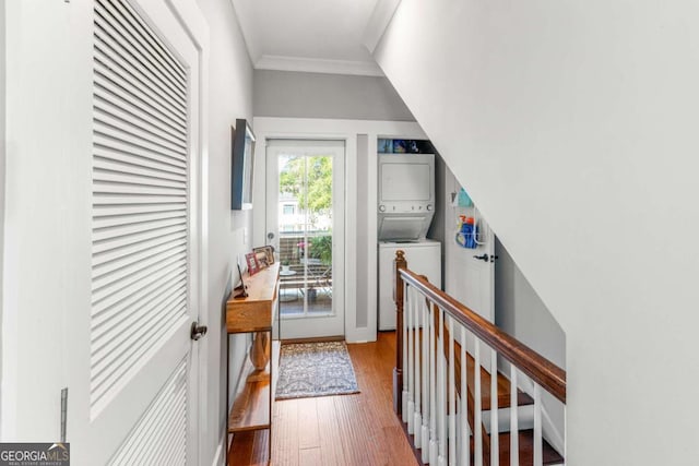 hall featuring stacked washer / drying machine, wood finished floors, and ornamental molding