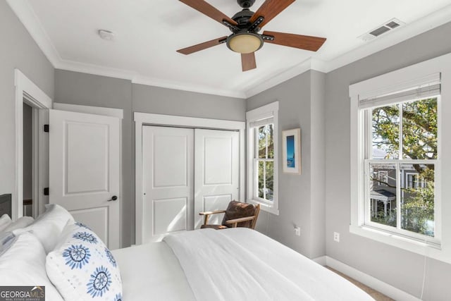 bedroom with crown molding, multiple windows, visible vents, and a closet