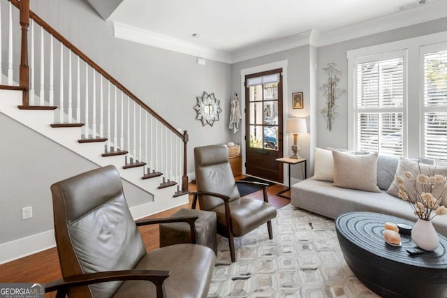 living room with light wood-type flooring, baseboards, ornamental molding, and stairs