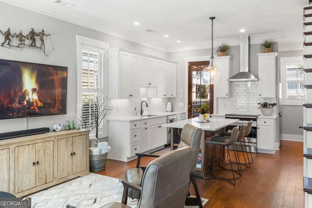 kitchen with a kitchen island, dark wood-type flooring, appliances with stainless steel finishes, and wall chimney exhaust hood