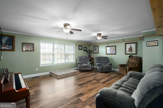 living room featuring a ceiling fan, crown molding, baseboards, and wood finished floors