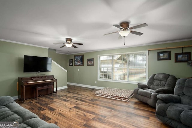 living room featuring a ceiling fan, crown molding, baseboards, and wood finished floors