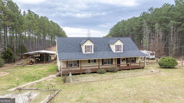 view of front of house with a detached carport, a front lawn, a view of trees, and covered porch