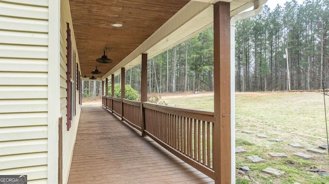 wooden terrace featuring a ceiling fan and a view of trees