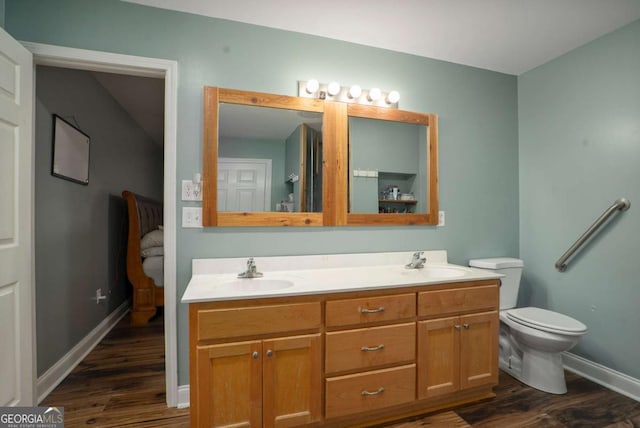 bathroom with a sink, toilet, wood finished floors, and double vanity