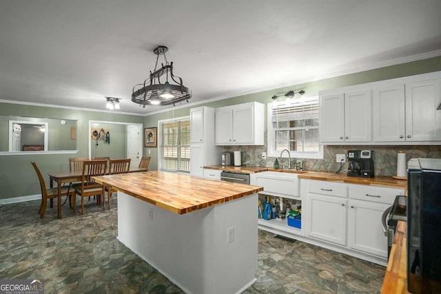 kitchen featuring butcher block countertops, decorative backsplash, white cabinets, stone finish flooring, and crown molding