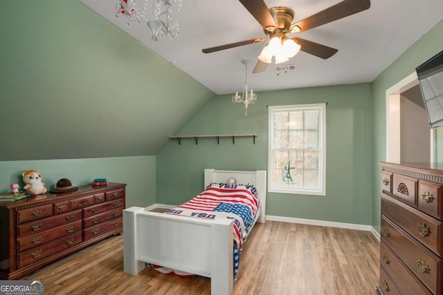 bedroom featuring visible vents, baseboards, lofted ceiling, wood finished floors, and a ceiling fan