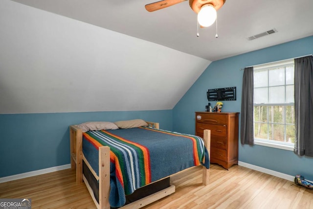 bedroom featuring visible vents, lofted ceiling, wood finished floors, baseboards, and ceiling fan