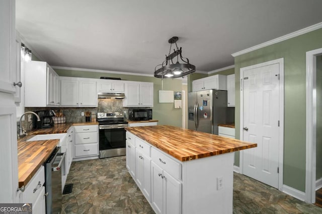 kitchen with butcher block countertops, ornamental molding, a sink, under cabinet range hood, and appliances with stainless steel finishes