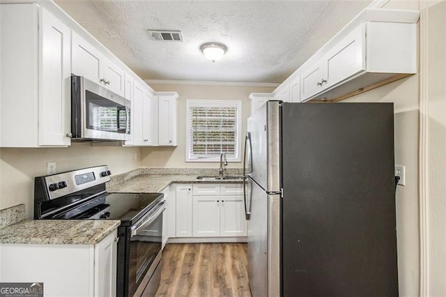 kitchen featuring visible vents, white cabinetry, stainless steel appliances, and a sink