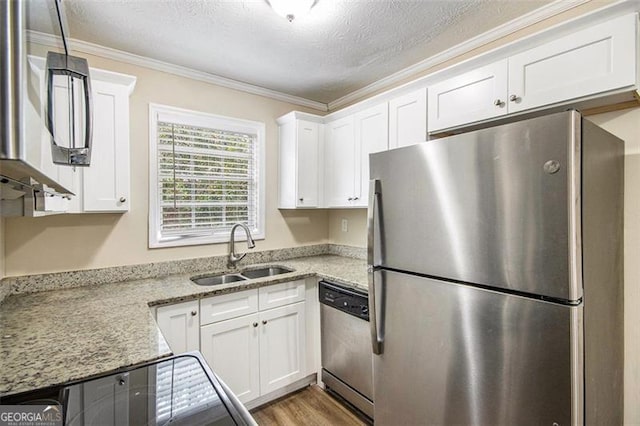 kitchen featuring ornamental molding, stainless steel appliances, wood finished floors, white cabinetry, and a sink