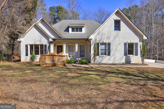 view of front of property featuring a front yard, a porch, and brick siding