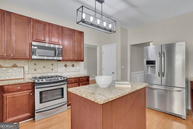 kitchen featuring backsplash, light wood-style flooring, stainless steel appliances, and light stone counters