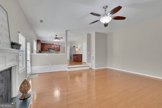 unfurnished living room featuring visible vents, light wood-style flooring, baseboards, and a premium fireplace