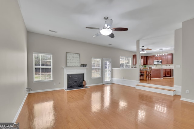 unfurnished living room with light wood finished floors, visible vents, plenty of natural light, and a fireplace