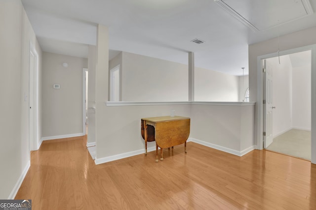 unfurnished room featuring visible vents, attic access, baseboards, and wood finished floors