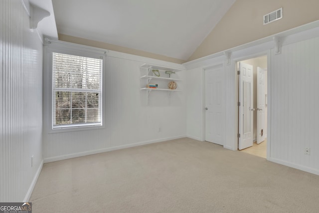 empty room featuring vaulted ceiling, carpet, visible vents, and baseboards