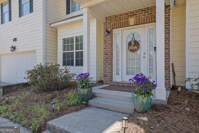 doorway to property featuring brick siding, covered porch, and a garage