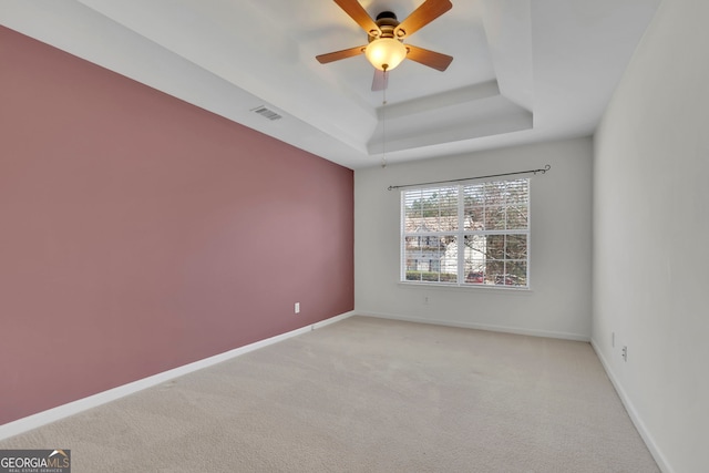 spare room with visible vents, a raised ceiling, and baseboards