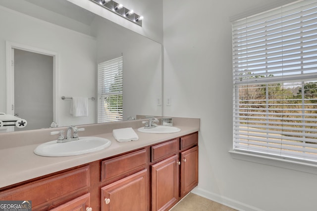 bathroom with double vanity, tile patterned flooring, baseboards, and a sink