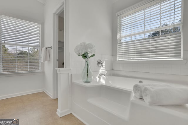 full bath with baseboards, a healthy amount of sunlight, a bath, and tile patterned flooring