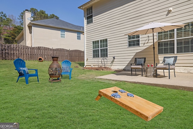 view of yard featuring a patio area, fence, and a fire pit