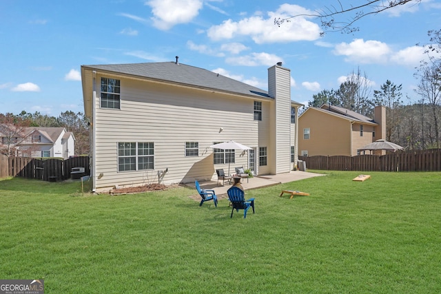 back of house with a patio area, a lawn, a chimney, and fence