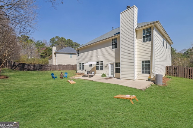 rear view of house featuring a lawn, a patio, a chimney, and a fenced backyard