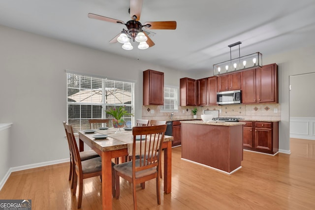 kitchen with light wood-type flooring, stainless steel microwave, backsplash, and decorative light fixtures