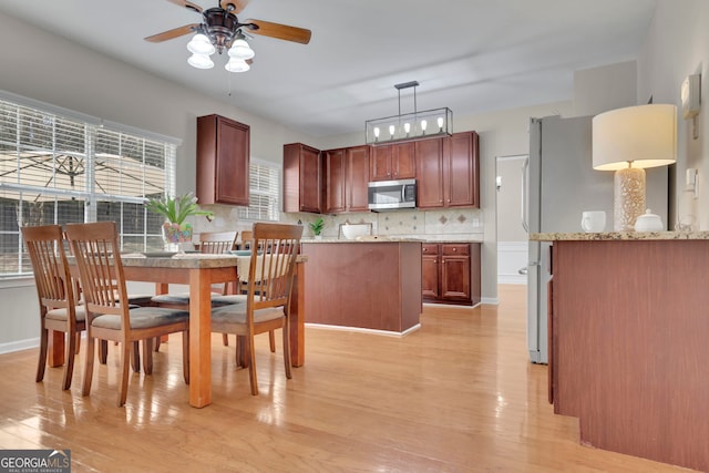 dining area featuring a ceiling fan, light wood-style floors, and baseboards