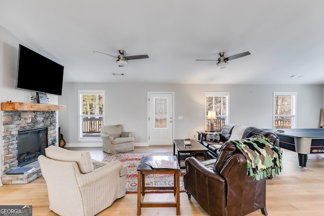 4864 Yeagar Rd, Douglasville, GA 30135 - living room with visible vents, a stone fireplace, a ceiling fan, and light wood finished floors